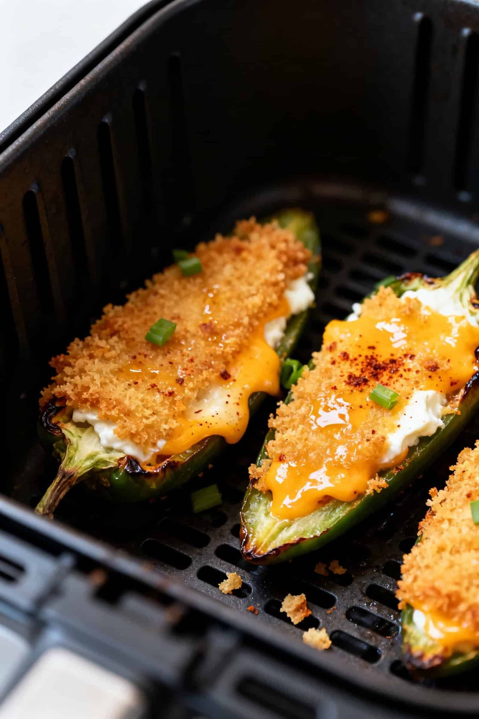 Close-up detail: Air fryer jalapeño poppers just out of the basket, cheese side up with golden pank
