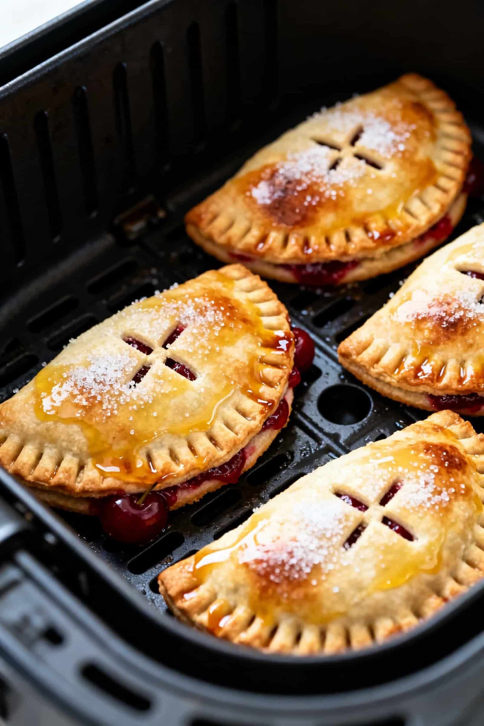 Close-up detail, cooking process: Mini cherry hand pies in an air fryer basket at 350°F, mid-cook,