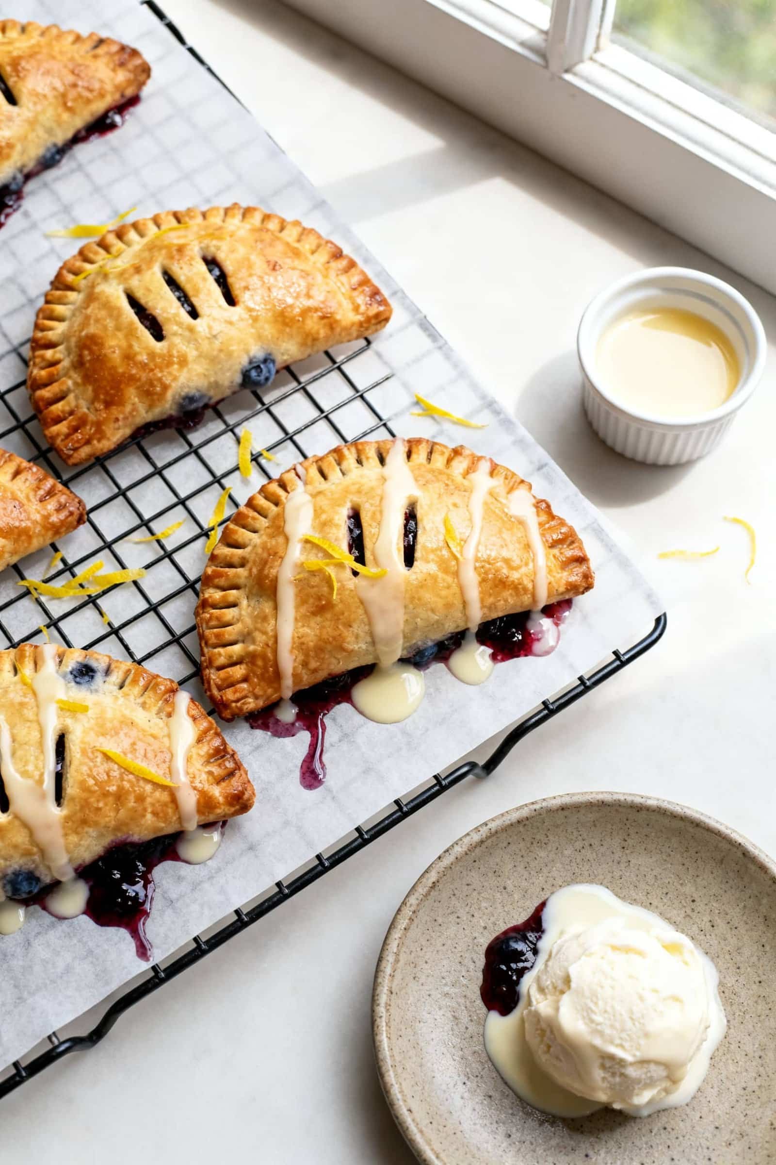 Final dish, tasty top view: Overhead shot of freshly cooked blueberry hand pies resting on a wire co